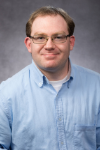 Picture of white man with glasses in a blue shirt.