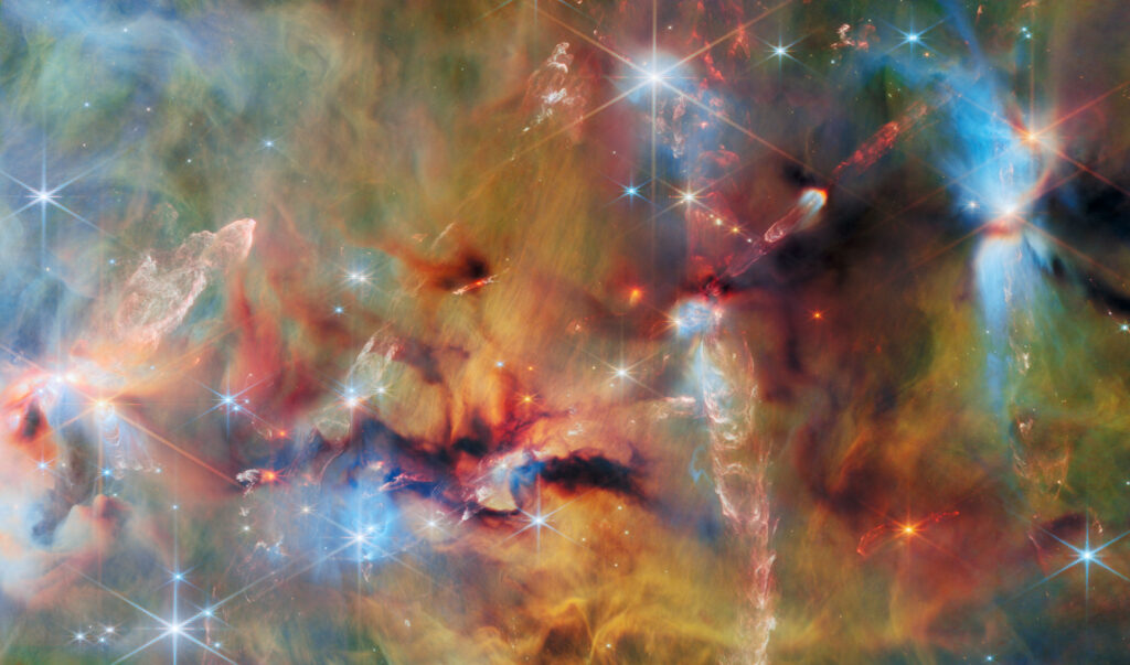 This image of space is covered with layers of gas and dust in blue, green and yellowish colours.