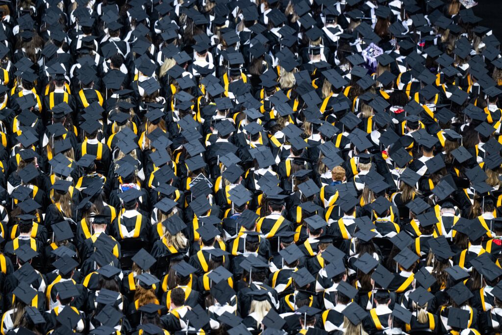 A large group of students in graduation caps and gowns sitting in chairs.